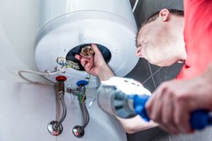 man in bathroom repairing electric boiler